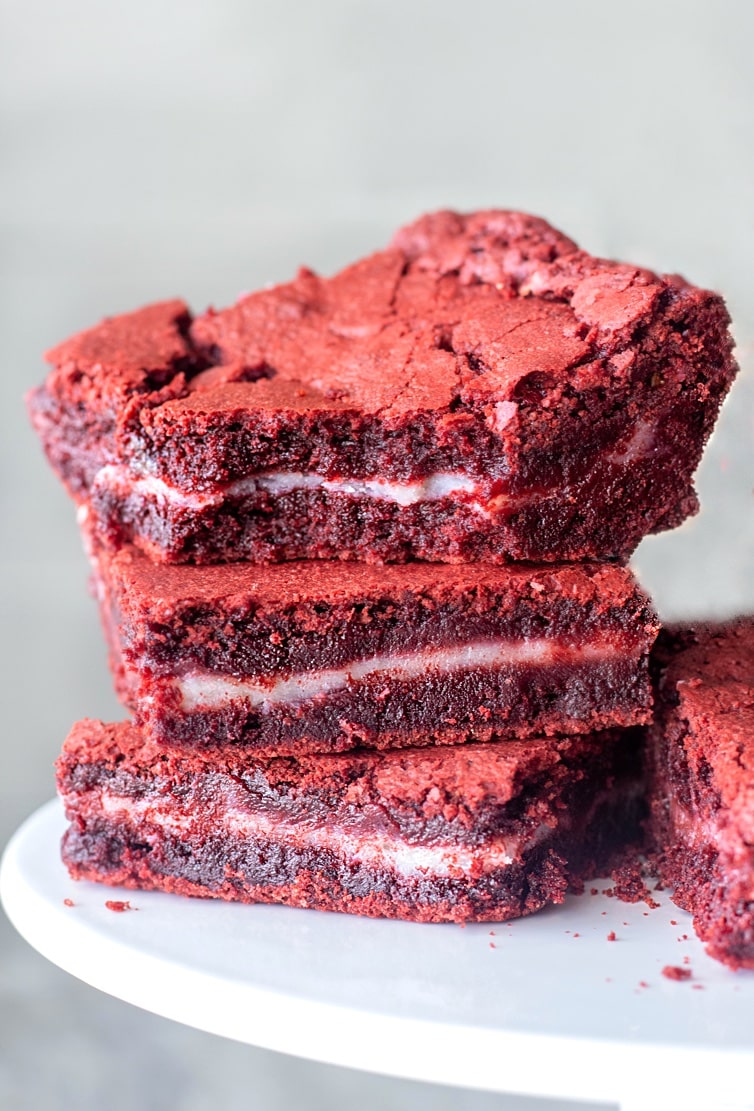 Fudgy Red Velvet Brownies stuffed with a surprise layer of Gooey Cream Cheese frosting. The perfect Valentines day dessert. 