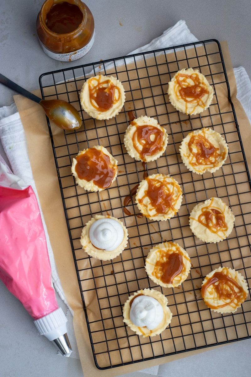 Mini banana pudding cheesecakes drizzled with salted caramel sauce.