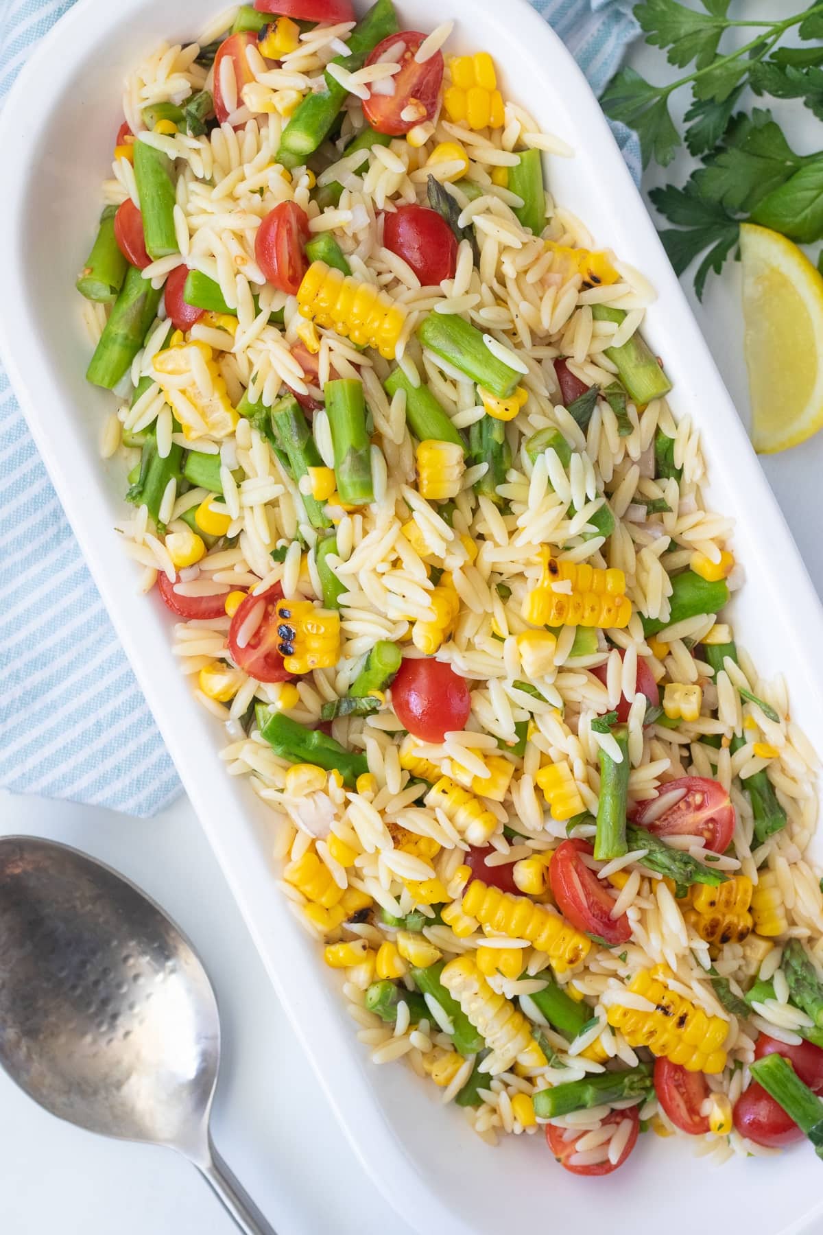 Summer orzo salad made with a quick lemon herb vinaigrette, cherry tomatoes, seared fresh corn, and asparagus.